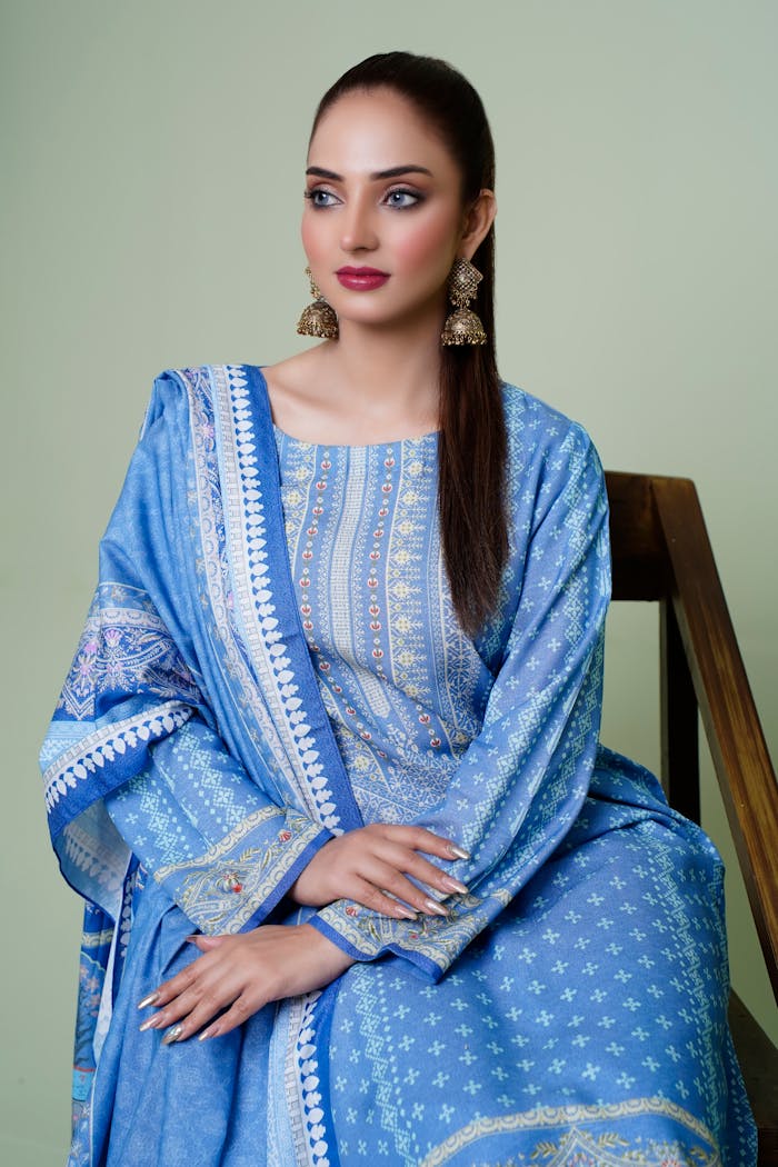 A model in blue traditional Indian attire poses elegantly indoors, highlighting fashion and cultural beauty.