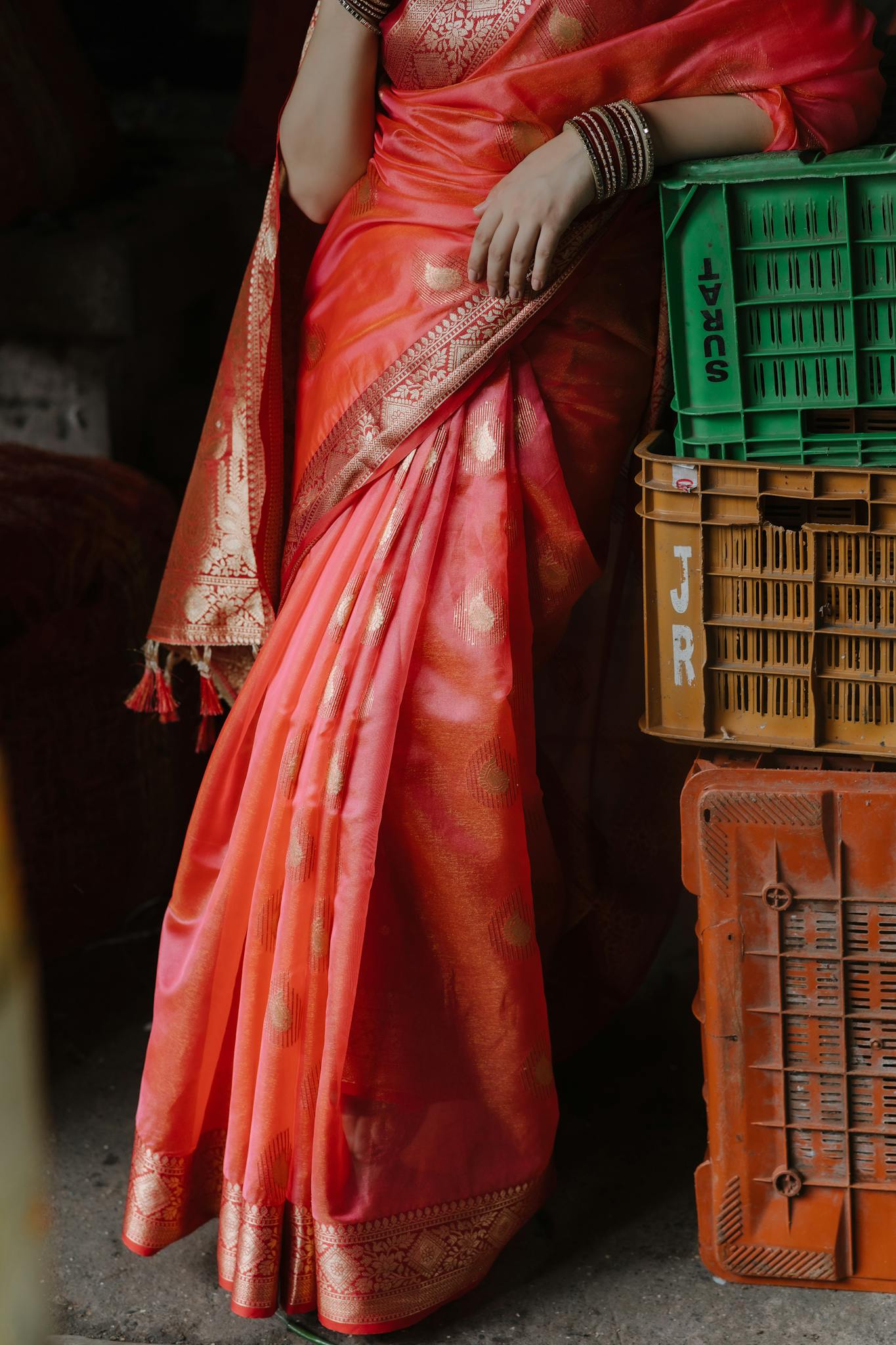 A close-up of a woman in a vibrant red saree with traditional jewelry, posed gracefully.